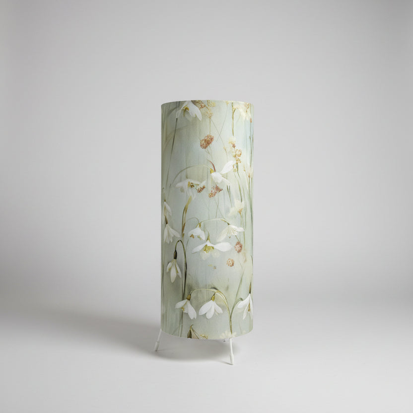 handmade cylindrical plug in lamp with tripod base and bayonet bulb.  cotton snowdrop fabric in pale green and blue table lamp with switch.  handmade lighting in made in UK. 15cm wide and 35cm tall table lamp for bedside table and cosy mood lighting.