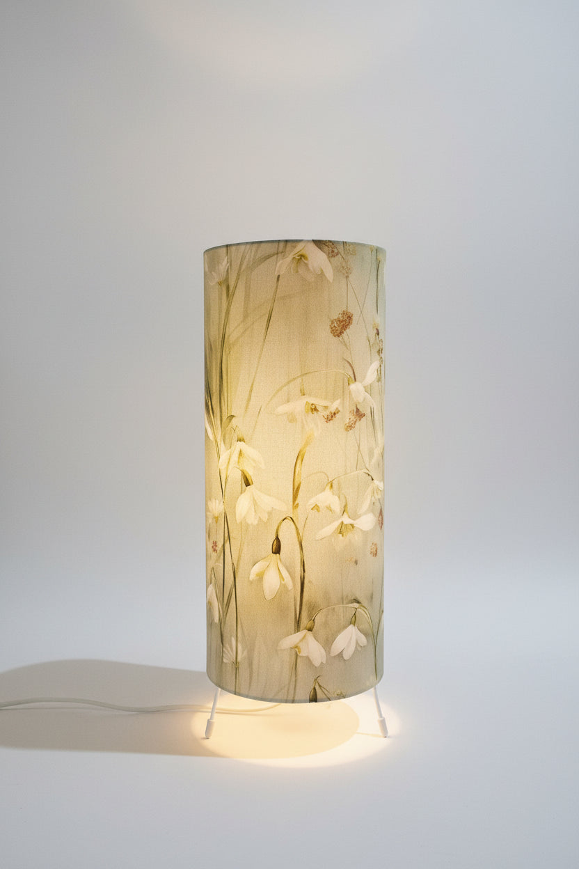 handmade cylindrical plug in lamp with tripod base and bayonet bulb.  cotton snowdrop fabric in pale green and blue table lamp with switch.  handmade lighting in made in UK. 15cm wide and 35cm tall table lamp for bedside table and cosy mood lighting.